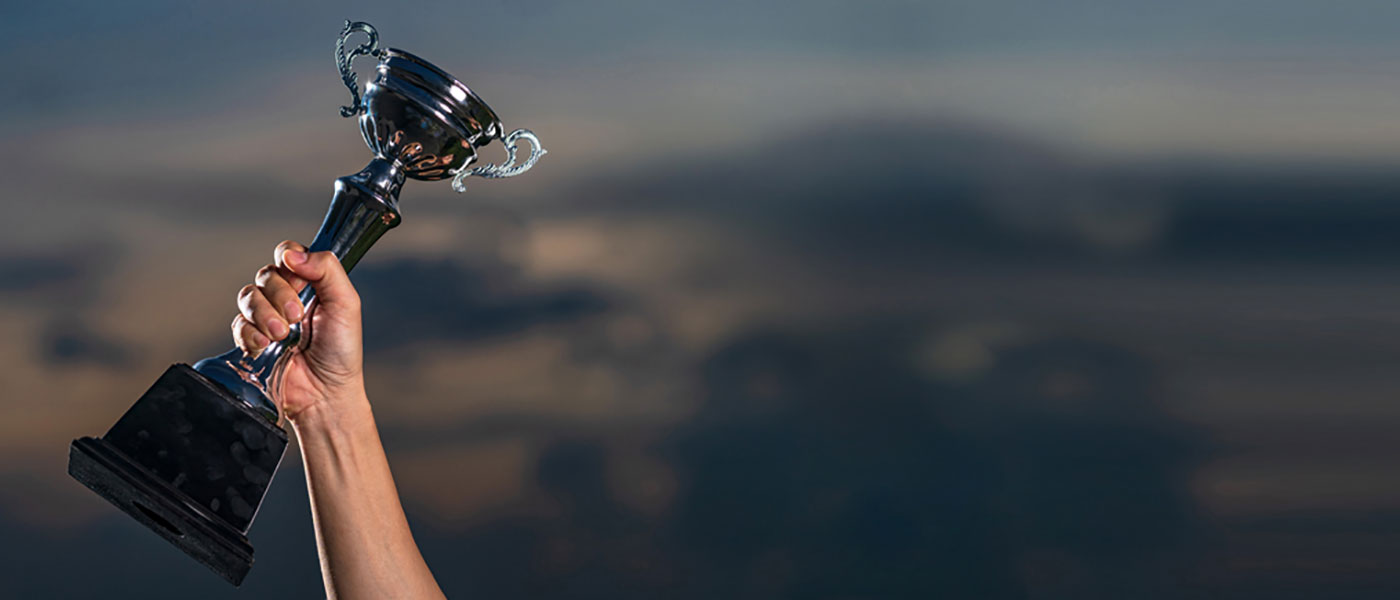 Banner - hand holding a gold trophy